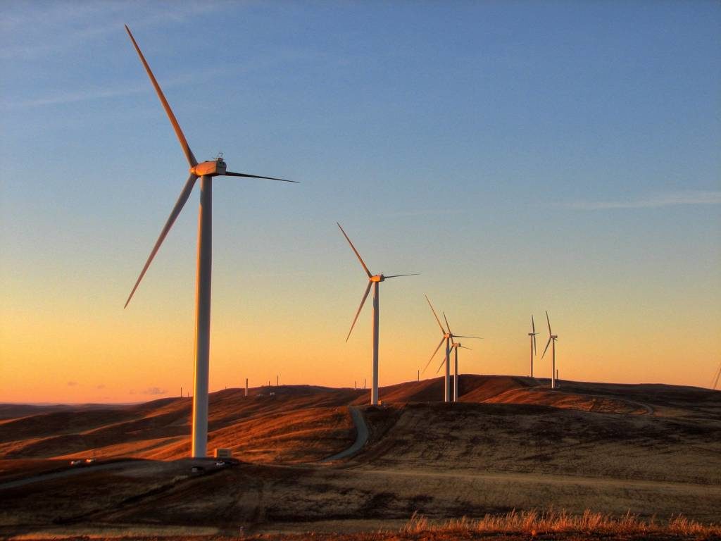Photo of a wind farm in rolling hills taken at sunset
