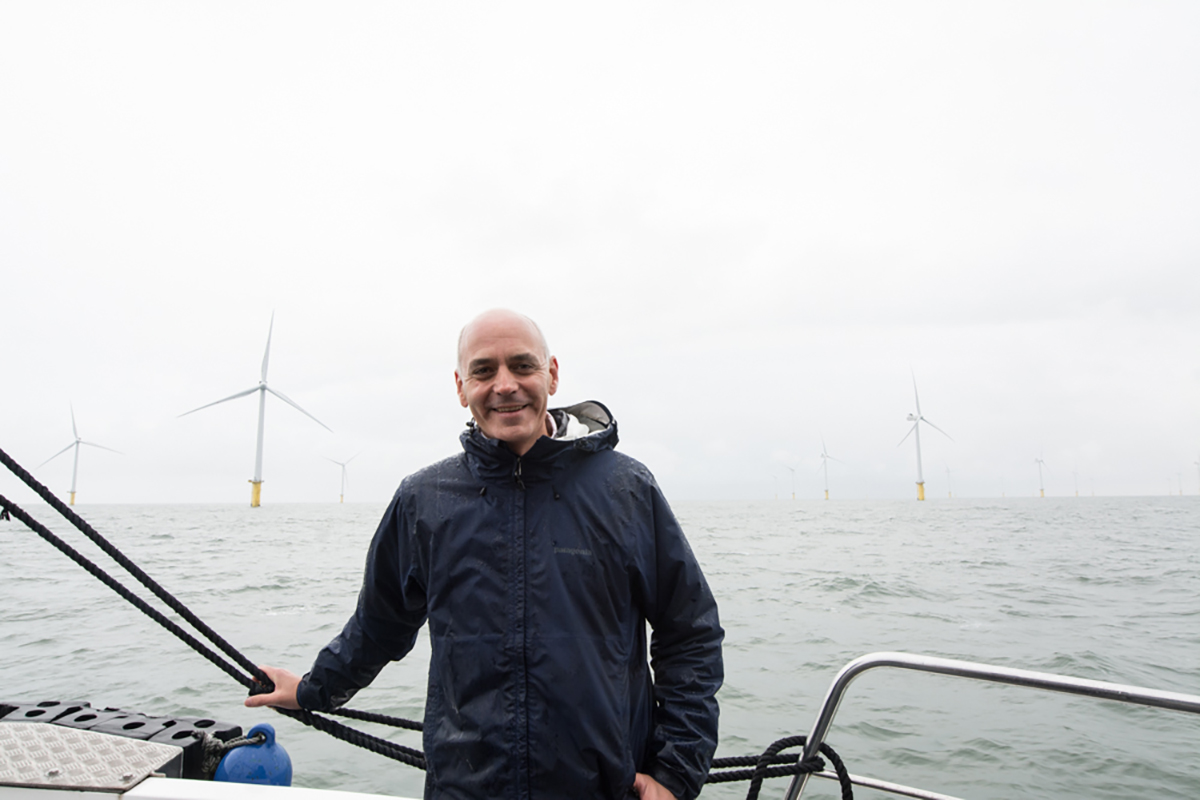 Martin Rice on a boat, with big wind turbines in the background