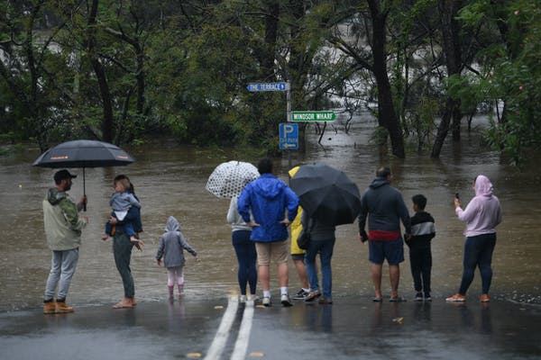 A family walking towards flood waters from the 2021 March floods