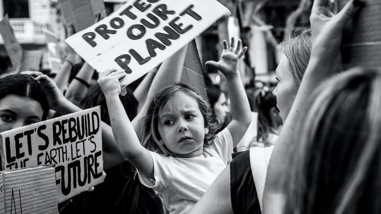 Black and white photo of a child holding up a placard at a climate rally 
