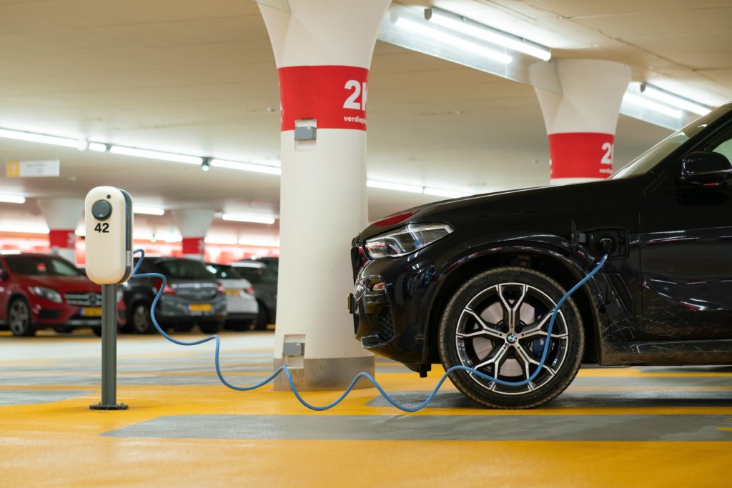 A black electric four-wheel drive plugged in and charging in a European parking lot.