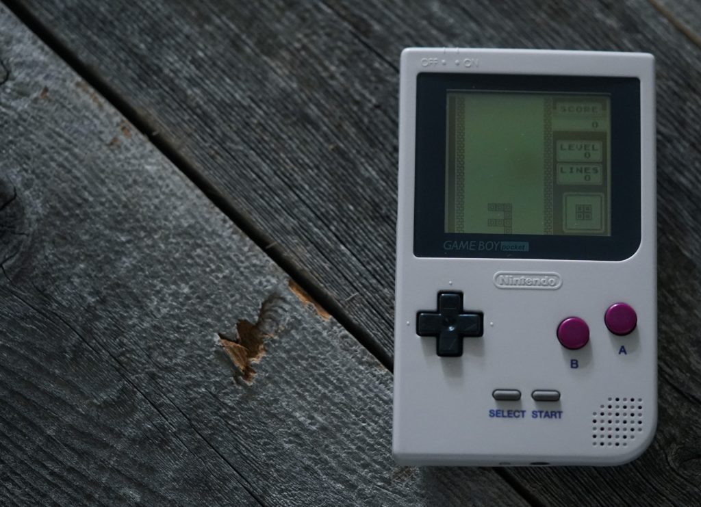 A Game Boy Pocket, playing Tetris, laid artfully on wooden planks.