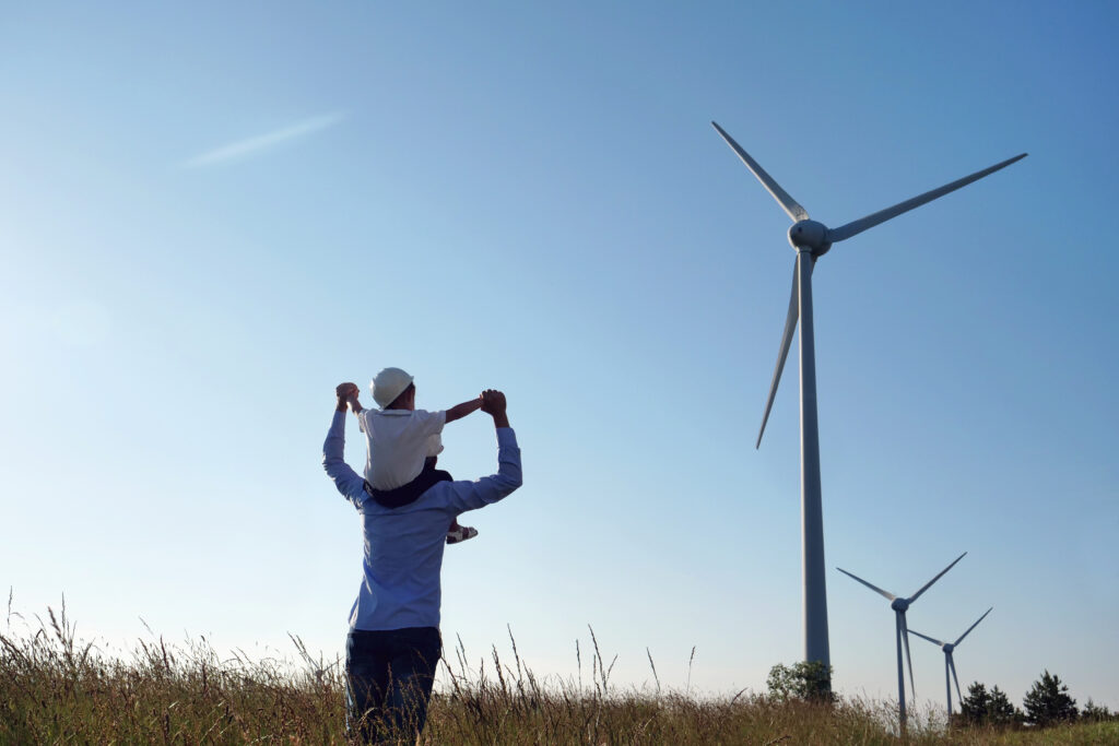 Child on shoulders in front of wind turbine