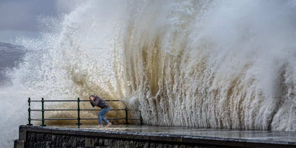 man protecting himself from huge wave ocean wave crashing.